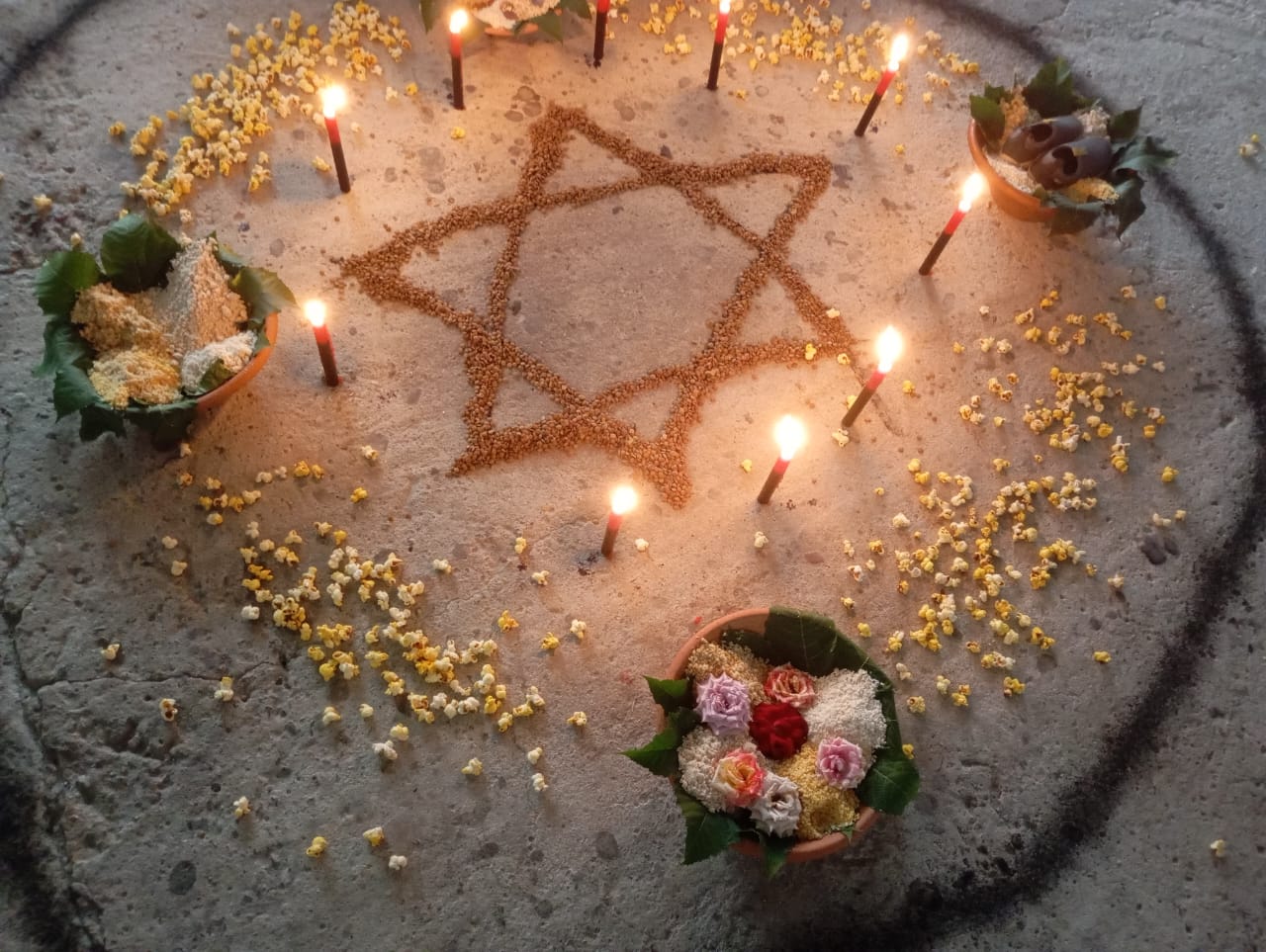 Símbolo ritual desenhado no chão com velas, flores e elementos sagrados.